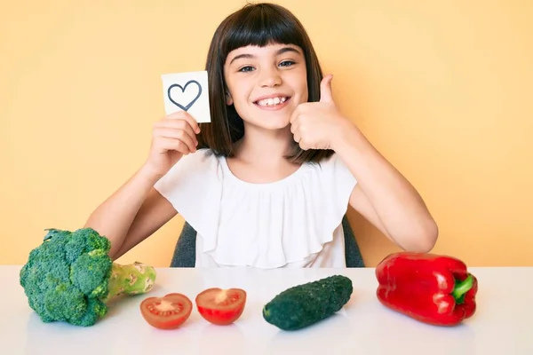 若いです女の子ともに座っているテーブルの上に野菜保持心を思い出させる笑顔幸せと正 親指アップします優れたと承認サイン — ストック写真