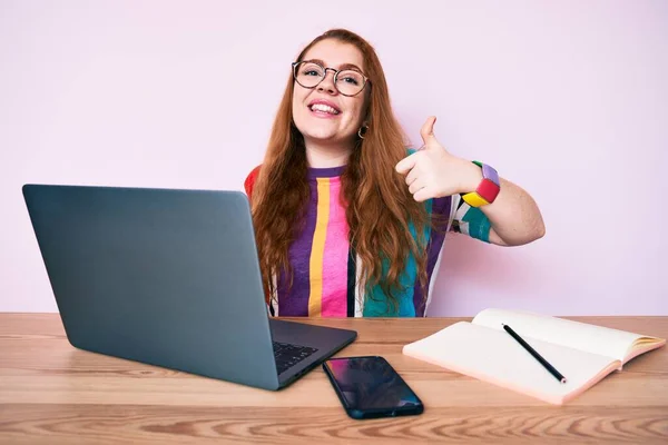 Ofiste Çalışan Genç Kızıl Saçlı Laptopuyla Mutlu Pozitif Gülümseyen Başparmağıyla — Stok fotoğraf