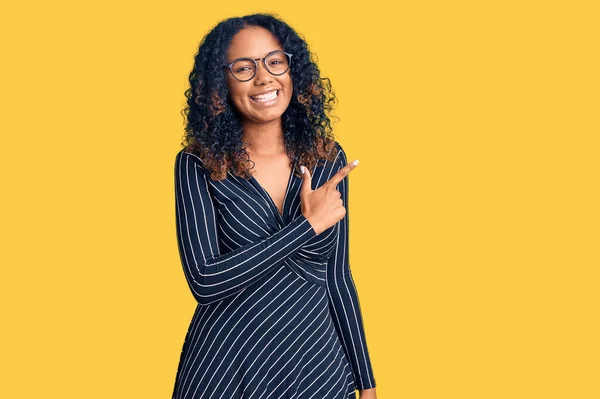 年轻的非洲裔美国女人 穿着休闲装 戴着眼镜 面带微笑 手指手画脚地朝旁边走去 脸上带着快乐而自然的表情 — 图库照片