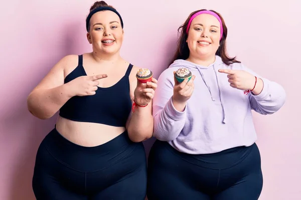 Young Size Twins Wearing Sportswear Holding Cupcake Smiling Happy Pointing — Stock Photo, Image