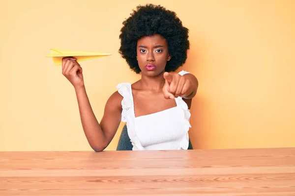 Young African American Woman Holding Paper Airplane Pointing Finger Camera — Stock Photo, Image