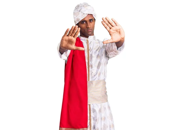 伝統的なシャーワニを身に着けているアフリカのハンサムな男は 手の手のひらと指 カメラの視点を使用してフレームを行う服を見た — ストック写真