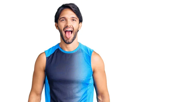変な表情で楽しそうに舌を突き出してスポーツウェアを着たハンサムなヒスパニック系の男 感情の概念 — ストック写真