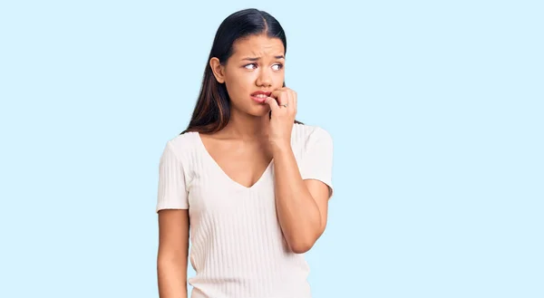 若い美しいラテン語の少女は 口の爪をかむ上で手でストレスと神経を見てカジュアルな白いTシャツを着ている 不安の問題 — ストック写真