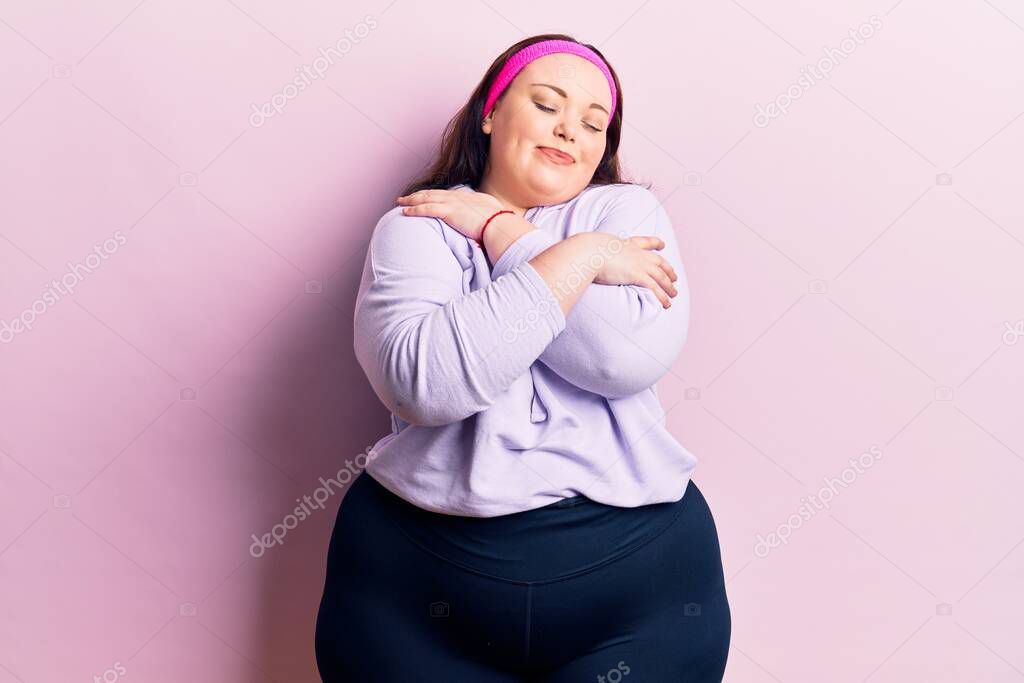 Young plus size woman wearing sportswear hugging oneself happy and positive, smiling confident. self love and self care 