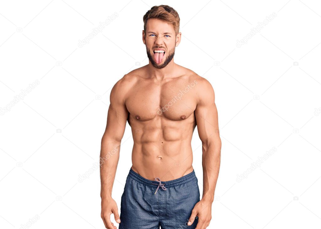 Young caucasian man standing shirtless sticking tongue out happy with funny expression. emotion concept. 
