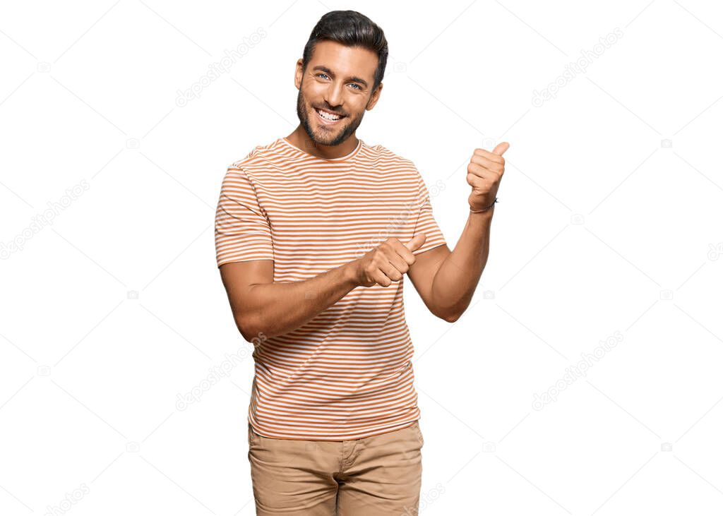 Handsome hispanic man wearing casual clothes pointing to the back behind with hand and thumbs up, smiling confident 