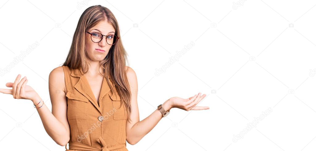 Young beautiful blonde woman wearing casual clothes and glasses clueless and confused with open arms, no idea concept. 