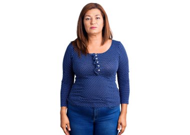 Yüzünde ciddi bir ifade olan gündelik kıyafetler giyen orta yaşlı Latin bir kadın. Basit ve doğal bir şekilde kameraya bakıyorsun.. 