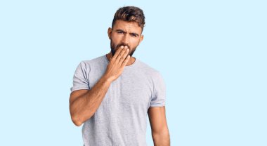 Gündelik kıyafetler giyen genç İspanyol adam ağzıyla ağzını kapatmaktan sıkılmış. Huzursuz ve uykulu.. 