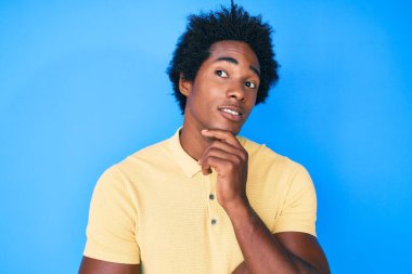 Yakışıklı Afro saçlı, sıradan giyinmiş, kuşkuya odaklanmış, çenesinde parmakları olan ve kafasını kaldırıp... 