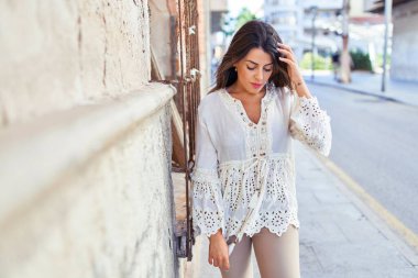 Güzel, genç bir kadın, şık kıyafetler giyip sokakta yürüyor.