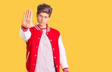 Beyzbol forması giyen yakışıklı genç adam avuç içiyle şarkı söylemeyi kesiyor. Yüzünde olumsuz ve ciddi bir jest olan uyarı ifadesi. 