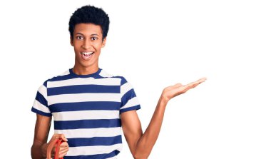 Genç Afro-Amerikan adam elinde süpermarket alışveriş sepeti tutarak zaferi mutlu bir gülümseme ve ellerini kaldırarak kazanan ifadeyle kutluyor. 