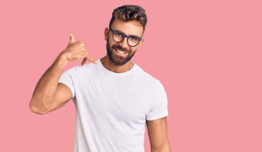 Günlük kıyafetler ve gözlük takan genç İspanyol adam gülümsüyor telefonla el ve parmak hareketleri yapıyor telefonda konuşuyor gibi. iletişim kavramları. 