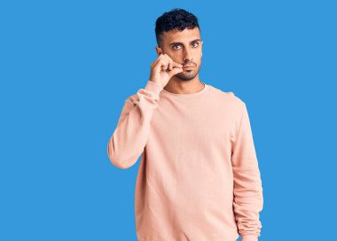 Gündelik kıyafetler giyen genç İspanyol adam ağzı ve dudakları parmaklarıyla kapanan fermuar gibi kapalı. gizli ve sessiz, tabu konuşması 