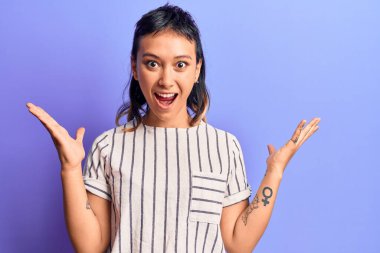 Gündelik giysiler giyen genç bir kadın zaferi mutlu bir gülümsemeyle kutluyor ve kazanan yüz ifadesi kaldırıyor. 