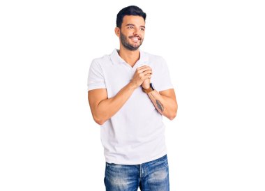 Genç, yakışıklı, günlük kıyafetler giyen, gergin ve heyecanlı, çenesi yan bakan bir İspanyol. 