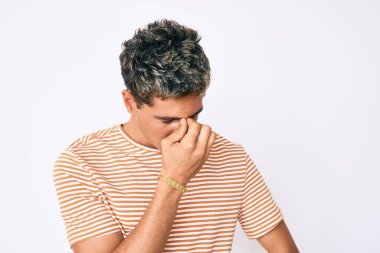 Gündelik kıyafetler giyen genç yakışıklı adam yorgun burnu ve gözleri ovuşturup yorgun ve baş ağrısı çekiyor. Stres ve hüsran kavramı. 