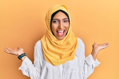 Geleneksel İslami başörtüsü takan genç esmer kadın çılgın kutlamalar yapıyor ve kollarını kaldırmış ve gözleri açık bir şekilde heyecanla haykırıyor. Kazanan konsept 