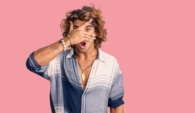 Yaz stili giyinmiş genç İspanyol adam şok içinde yüzünü ve gözlerini kapayarak utangaç ifadesiyle parmaklarının arasından bakıyor.. 