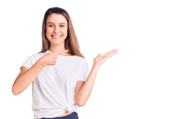 Gündelik tişört giyen genç ve güzel bir kız kameraya hayret ediyor ve gülümsüyor.. 