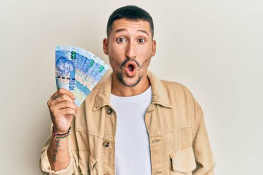 Dövmeleri olan yakışıklı bir adam Güney Afrika 'da 100 rand' lik banknotlar tutuyor. Şaşırmış ve şaşırmış bir şekilde ağzı açık, inançsız bir yüz. 