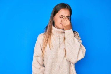 Güzel beyaz kadın yün kazak giyip yorgun burnu ve gözleri ovuşturup yorgunluk ve baş ağrısı çekiyor. Stres ve hüsran kavramı. 