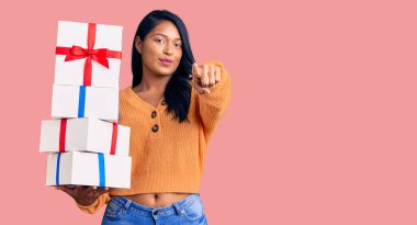 Uzun saçlı İspanyol kadın kamerayı işaret eden hediyeler tutuyor ve sen kendine güvenen ciddi bir hareket yapıyorsun. 