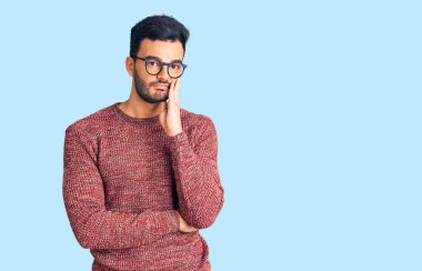 Kışlık süveter ve gözlük takan yakışıklı genç adam kollarını kavuşturarak depresyondan sıkılmış ve yorgun göründüğünü düşünüyor.. 