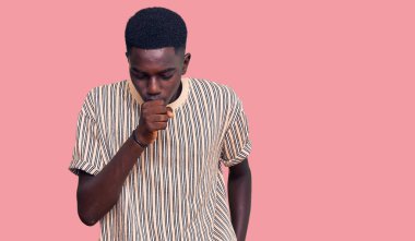 Genç Afro-Amerikalı bir adam günlük giysiler giyiyor kendini iyi hissetmiyor ve soğuk algınlığı veya bronşitin belirtisi olarak öksürüyor. sağlık hizmeti kavramı. 