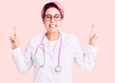 Pembe saçlı, doktor üniforması giyen genç ve güzel bir kadın umut ve gözlerin kapalı bir şekilde gülümseyerek bana işaret ediyor. Şans ve batıl inançlar. 