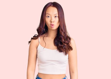 Genç, güzel Çinli kız günlük kıyafetler giyip dudaklarıyla balık suratı yapıyor. Çılgınca ve komik bir jest. Komik ifade. 