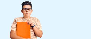 Küçük çocuk elinde gözlüklerle kitap tutuyor dudaklarıyla balık suratı yapıyor, çılgınca ve komik hareketler yapıyor. Komik ifade. 