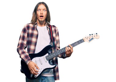 Uzun saçlı yakışıklı beyaz adam elektro gitar çalıyor. Korkmuş ve ağzı açık kalmış, şaşırmış, inançsız. 