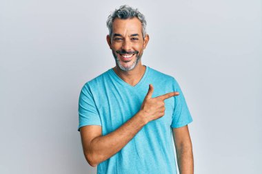 Orta yaşlı, gri saçlı, günlük kıyafetler giyen, neşeli, yüzünde mutlu ve doğal bir ifadeyle elleri ve parmaklarıyla yüzünü gösteren bir gülümseme olan bir adam. 