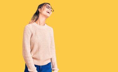 Kış süveteri giyen, gözlüklü, yüzünde gülümseme, doğal bir ifade olan genç ve güzel bir kadın. Kendinden emin gülen. 