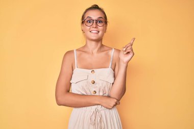 Yüzünde kocaman bir gülümseme olan beyaz elbiseli güzel bir kadın, kameraya el ve parmak ile bakıyor.. 