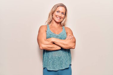 Orta yaşlı, beyaz, spor kıyafetleri giyen, kollarını kavuşturup kameraya gülümseyen sarışın kadın. pozitif kişi. 