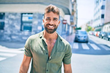 Genç İspanyol adam gülümseyerek şehirde mutlu bir şekilde yürüyor.