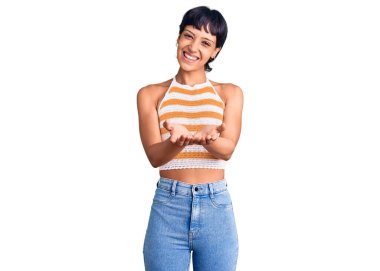 Kısa saçlı, sıradan kıyafetler giyen, avuçlarıyla gülümseyen ve el hareketi yapan esmer bir kadın. Bekleme ve koruma 