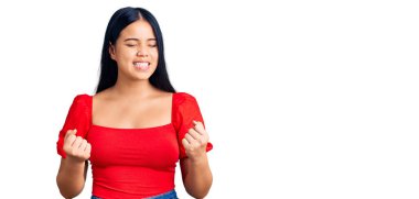 Genç, güzel Asyalı bir kız, sıradan kıyafetler giyiyor. Başarı için heyecanlı, kolları havada ve gözleri kapalı zaferi kutlarken gülümsüyor. Kazanan konsept. 