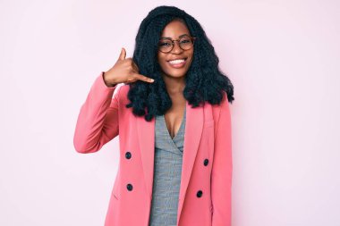 İş ceketi ve gözlük takan, gülümseyen, el ve parmaklarıyla telefon hareketi yapan, telefonda konuşan güzel Afrikalı bir kadın. iletişim kavramları. 