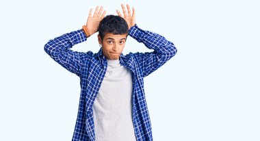 Genç Afro-Amerikalı sıradan kıyafetler giyen tavşan kulağı hareketi yapan, avuçlarıyla alaycı ve şüpheci görünen bir adam. Paskalya tavşanı konsepti. 