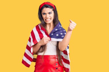 Amerika Birleşik Devletleri bayrağını tutan esmer genç kız öfkeyle bağırıyor, öfkeyle bağırıyor ve el kaldırıyor. 