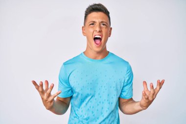 Genç İspanyol çocuk gündelik kıyafetler giyip deli gibi bağırıyor ve agresif bir ifade ve kollarla bağırıyor. hüsran kavramı. 