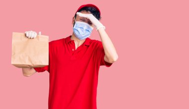 Teslimat üniforması giyen ve elinde kağıt torba tutan İspanyol asıllı genç bir adam. 