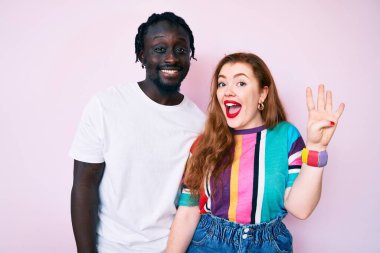 Farklı ırktan çiftler gündelik kıyafetler giyip dört numarayı gösteriyorlar ve mutlu bir şekilde gülümsüyorlar.. 