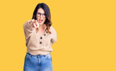 Güzel, genç, esmer, sıradan kıyafetler giyen ve gözlüklü bir kadın kameraya kızgın ve sinirli olduğunu gösteriyor. 