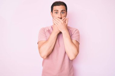 Gündelik tişört giyen genç yakışıklı adam yanlışlıkla elleri ile ağzını kapatırken şok oldu. gizli kavram. 